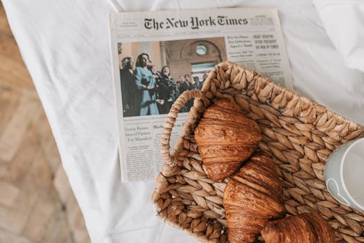 A cozy breakfast scene with croissants in a basket and a newspaper on a table, creating a relaxing morning vibe.