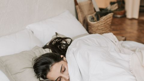 A peaceful woman sleeping comfortably in a cozy, minimalistic bedroom.