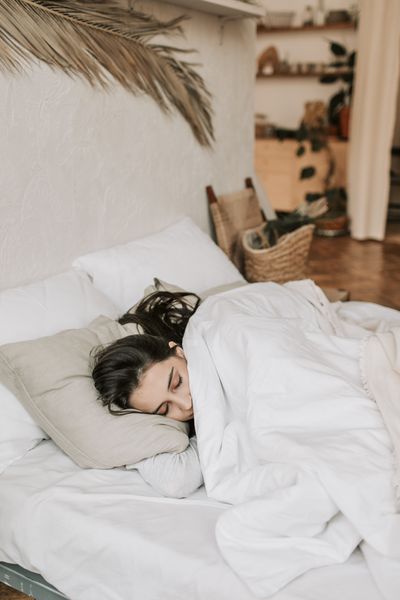 Person resting in bed under soft light, photo by Vlada Karpovich on Pexels