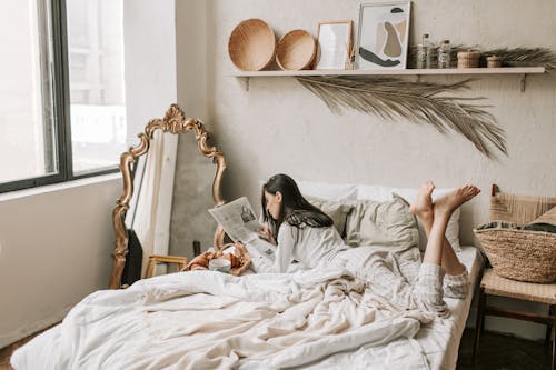 Free A Woman Reading a Newspaper in Bed Stock Photo