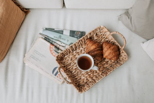 A cozy morning scene with coffee, croissants, and a woven tray on a white sofa.