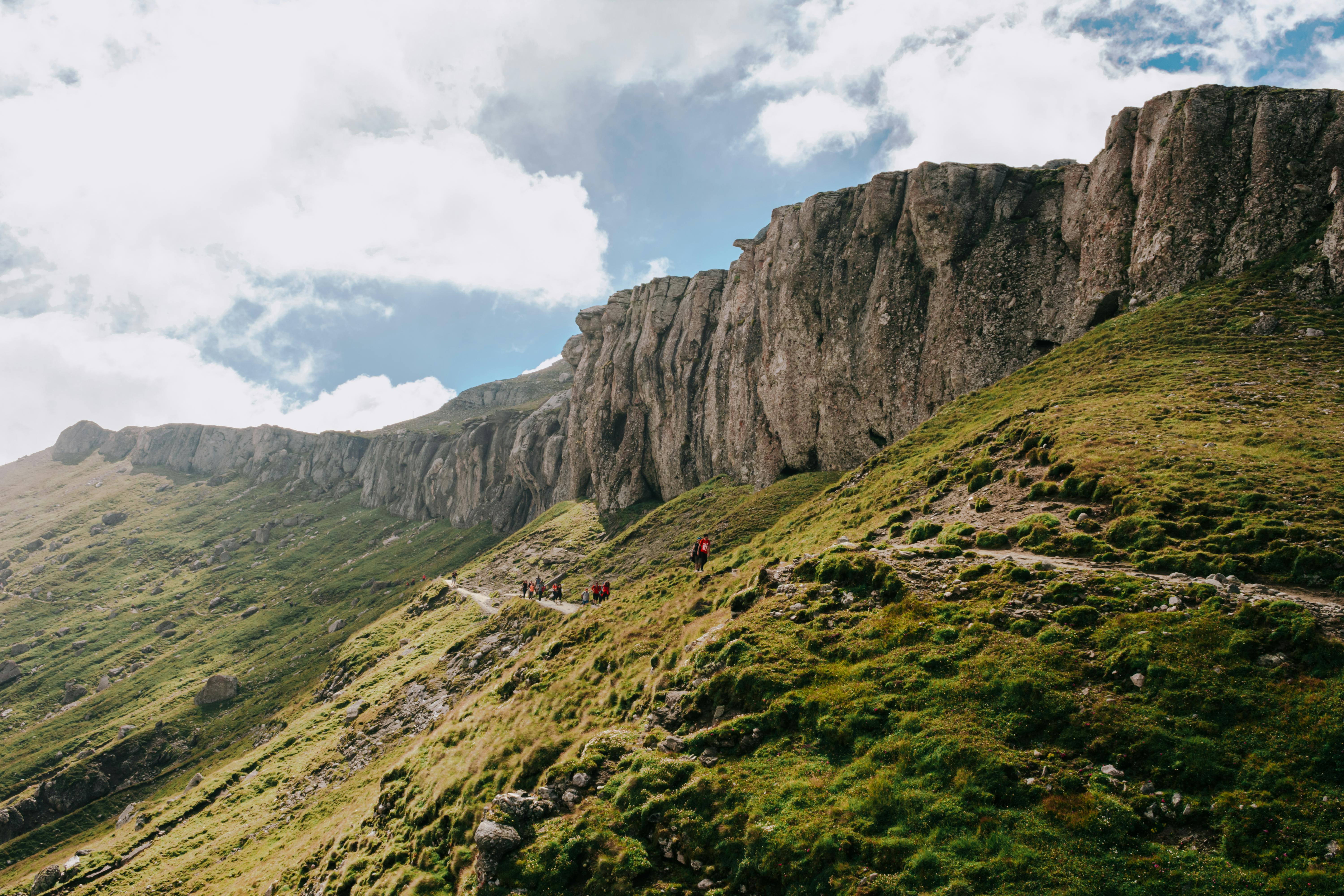 A group of hikers enjoys a scenic trail along rocky cliffs in Romania, a perfect adventure destination.