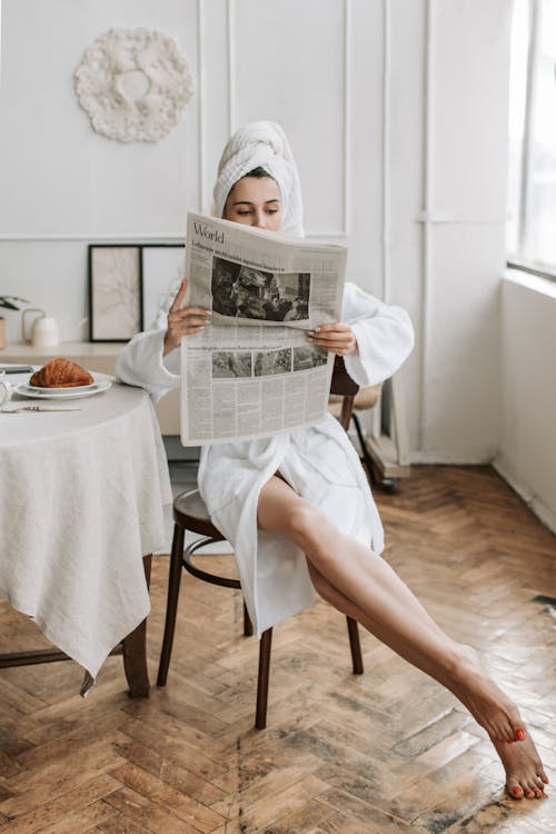 Free A Woman Reading A Newspaper in Her Bathrobe Stock Photo