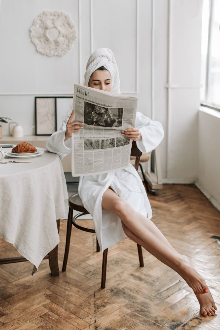 A Woman Reading A Newspaper In Her Bathrobe