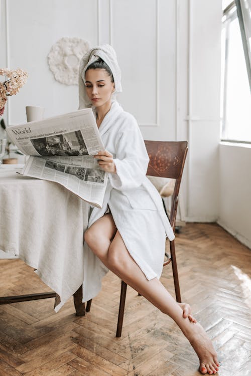Free Woman in White Robe Reading Newspaper Stock Photo