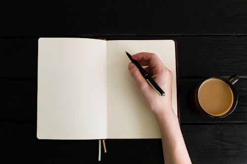 Free A Person Holding a Pen on the Blank Page of the Notebook Stock Photo