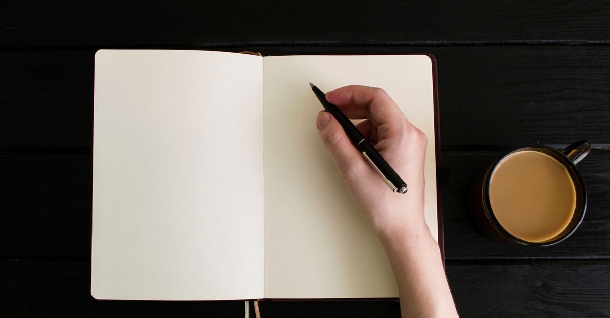 tired creative person with coffee staring at blank notebook