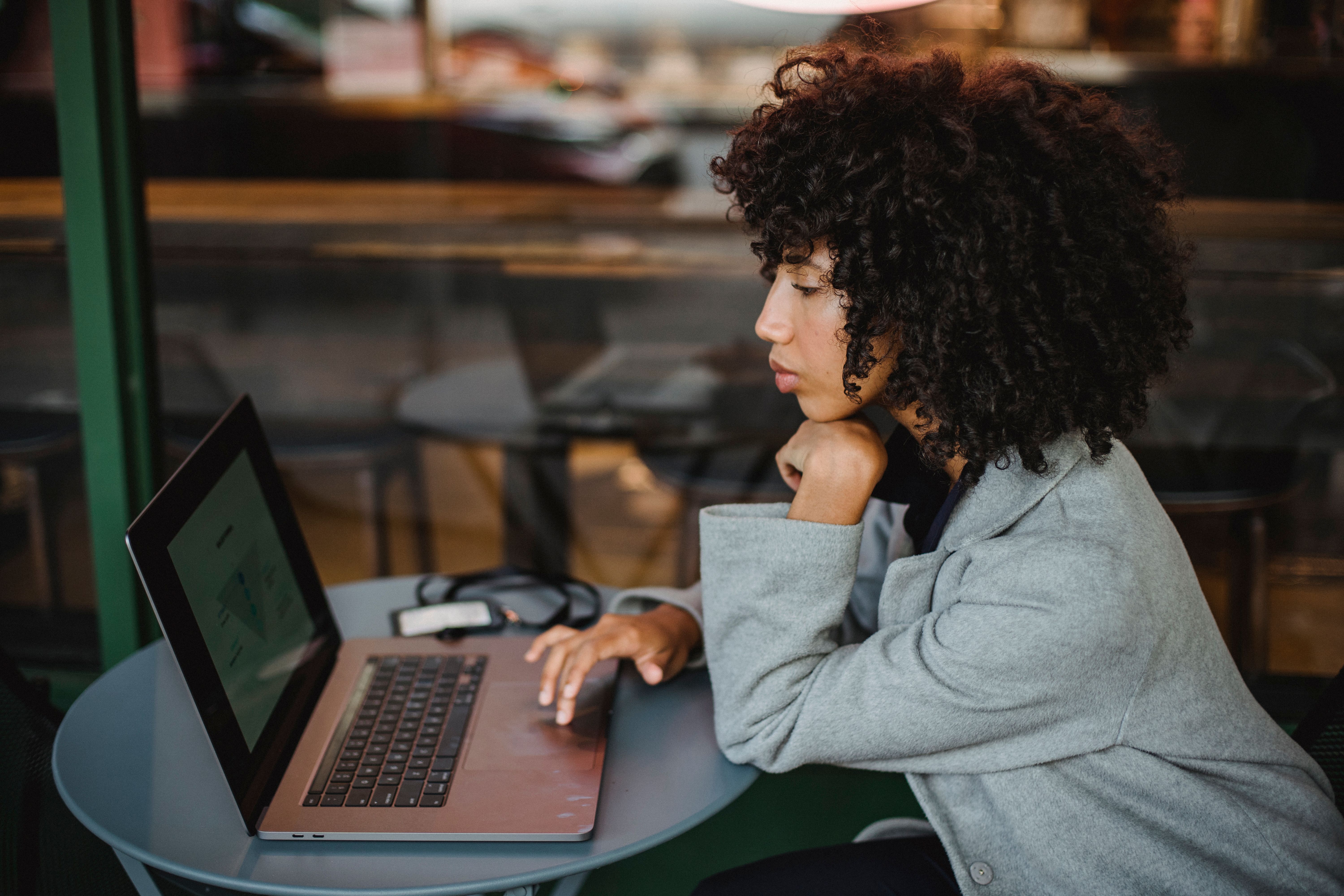 Young woman focused on her laptop while working at a cozy coffee shop.