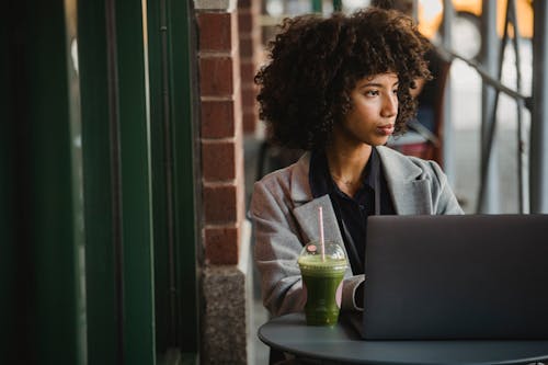 Photograph of a Woman Working with a Green Drink in a Plastic Cup