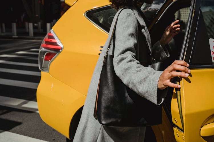 A Person In Gray Blazer With Leather Bag Standing Beside Yellow Car