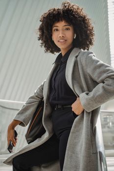 Confident businesswoman posing with elegance in urban environment, exuding professionalism.
