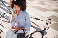 Woman in White Long Sleeve Shirt Sitting on Brown Wooden Bench