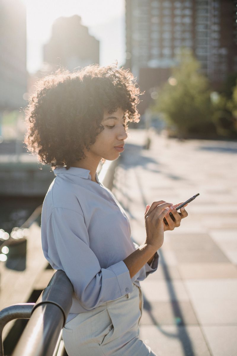 Portrait of a young woman with curly hair using her smartphone outdoors — photo by Roberto Hund on Pexels