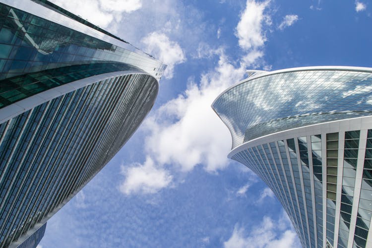 Tall Glass Buildings Under Blue Sky With White Clouds