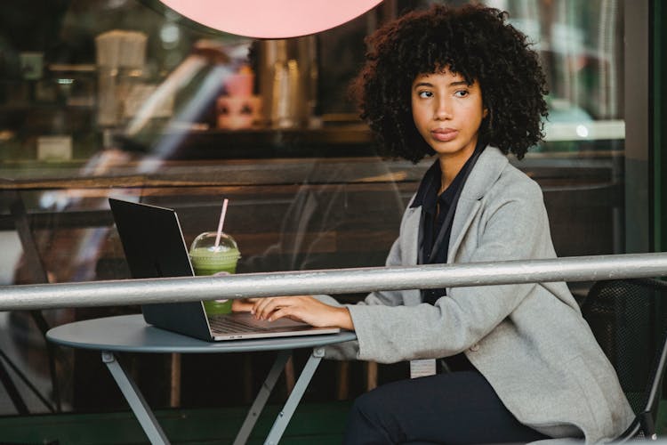 Woman In Gray Blazer Sitting Near Glass Window