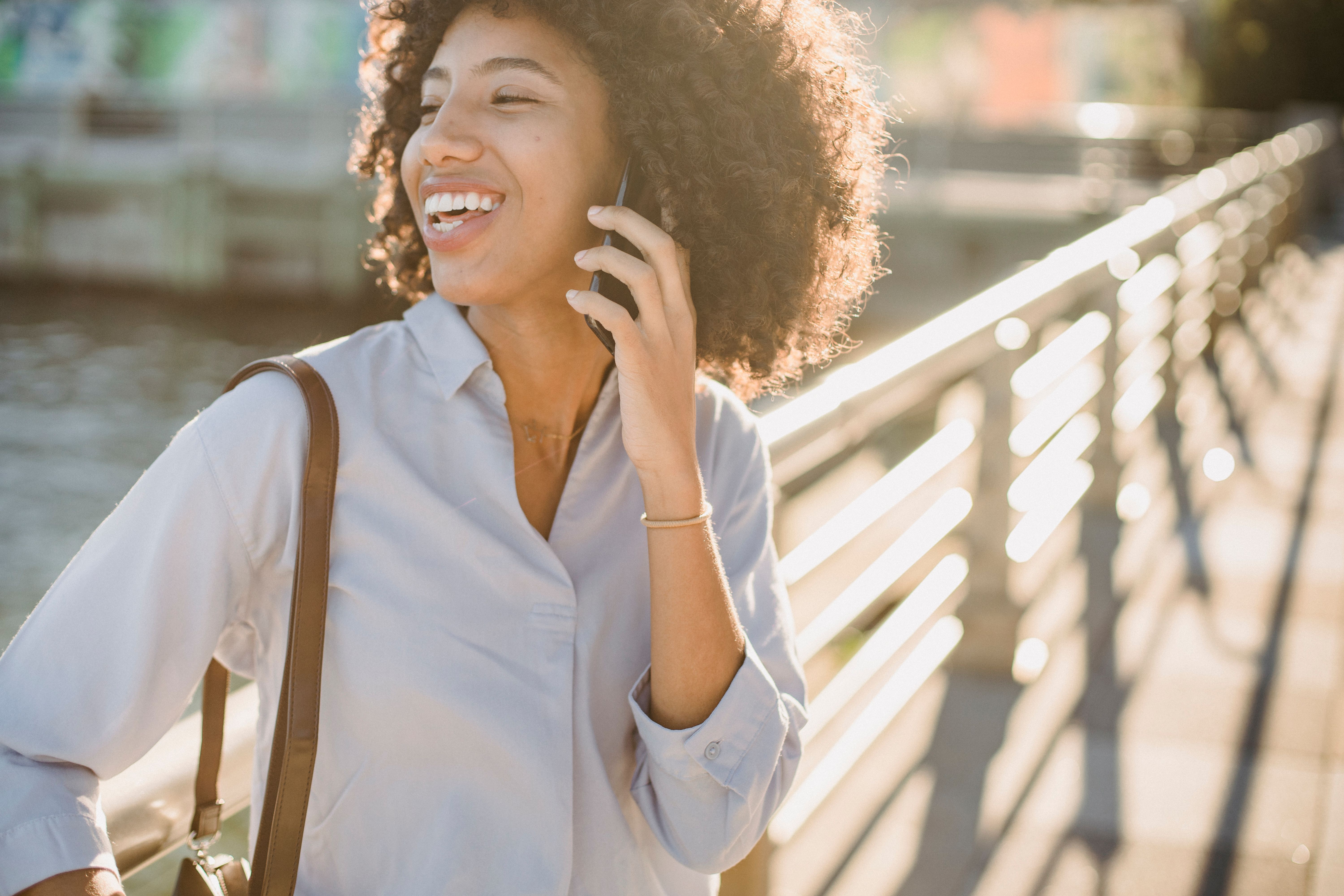 Person walking with a phone in hand, smiling, neighborhood setting