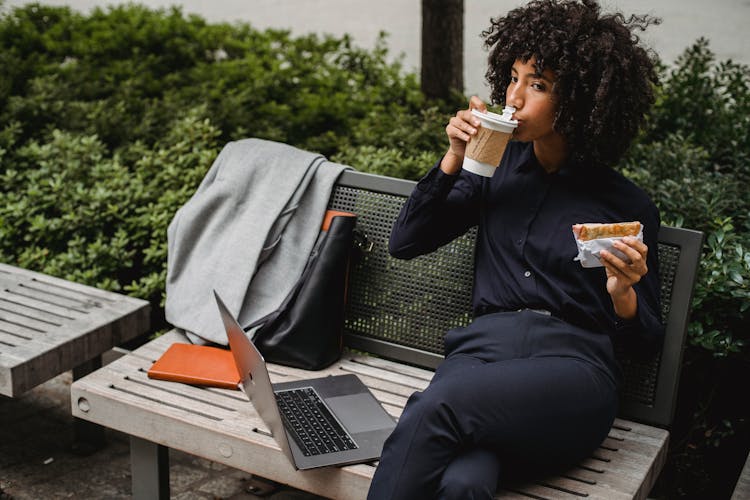 Woman Sitting On Bench Sipping Coffee