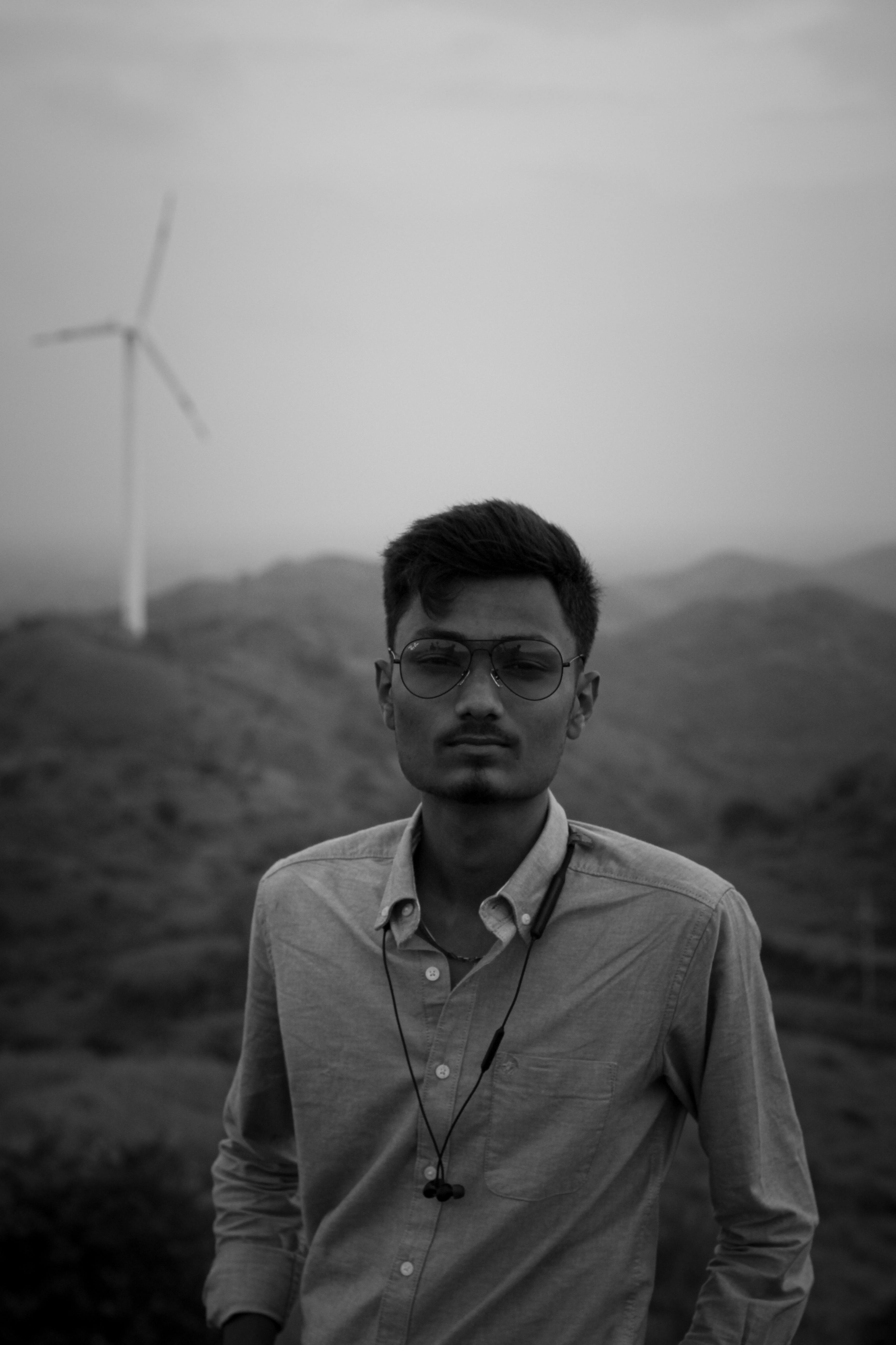 Black and white portrait of a man outdoors with a wind turbine in the background