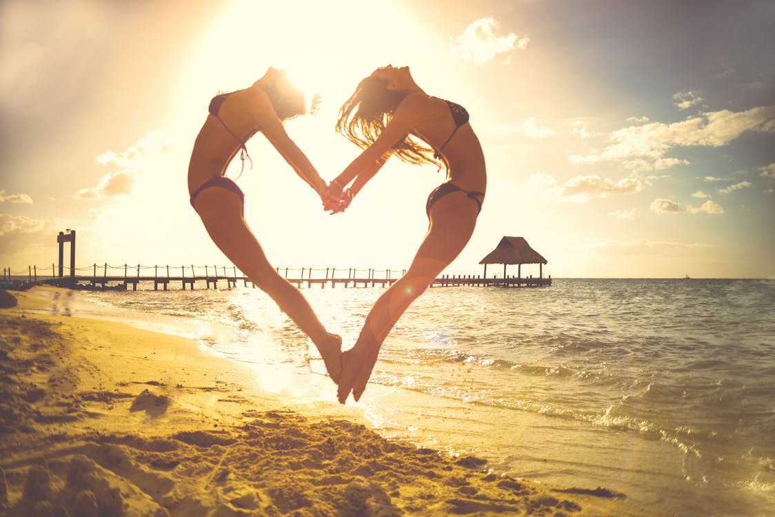 Free Two Woman Forming Heart at the Shore Stock Photo