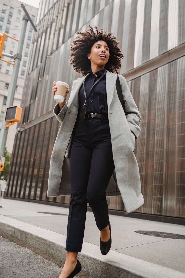 Woman In Gray Coat Stepping Down From Pavement