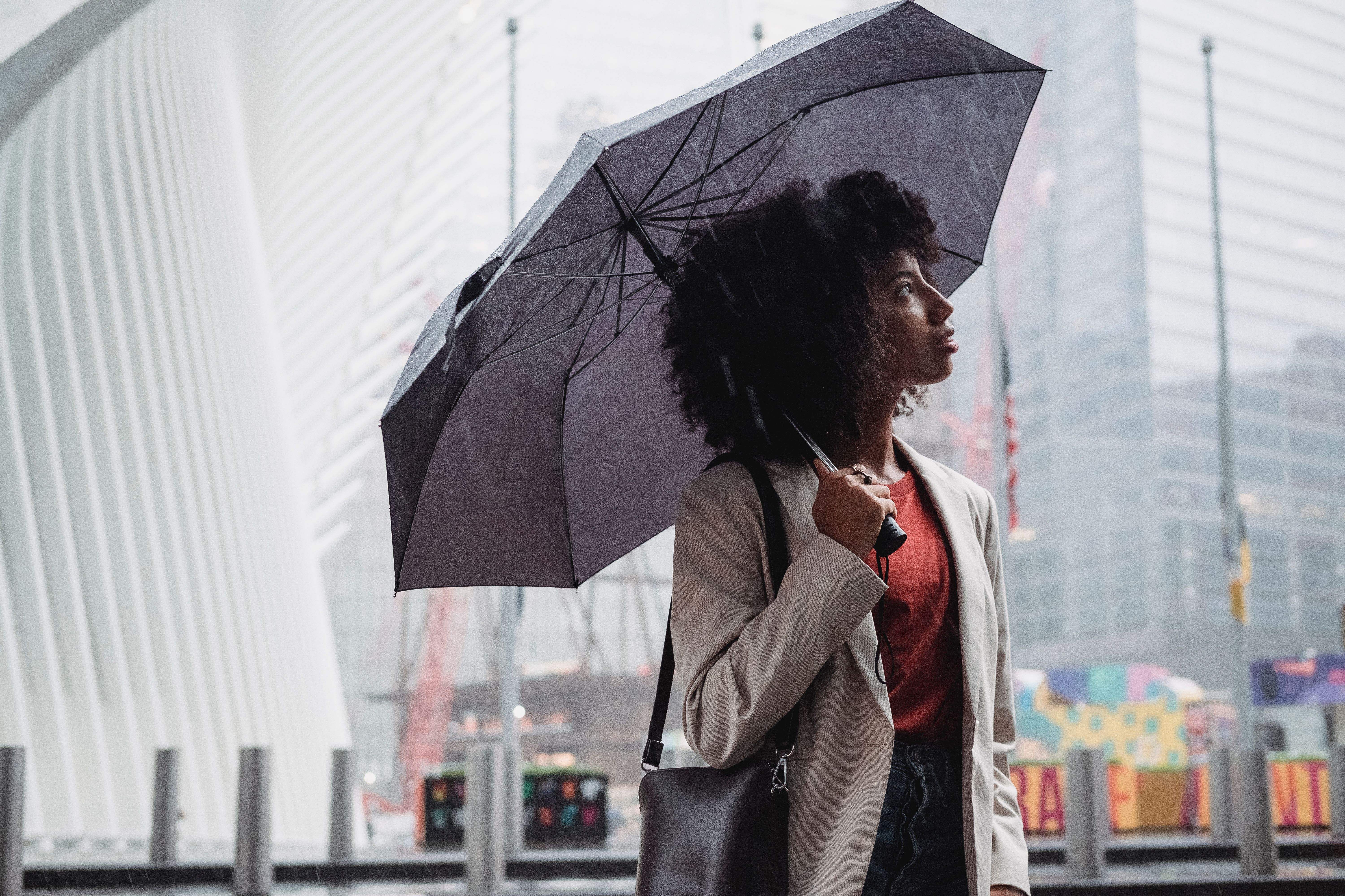 一个女人撑着雨伞，在多雨的城市天空下捕捉城市生活