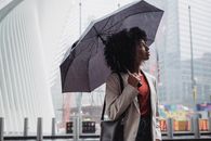 一个女人撑着雨伞，在多雨的城市天空下捕捉城市生活