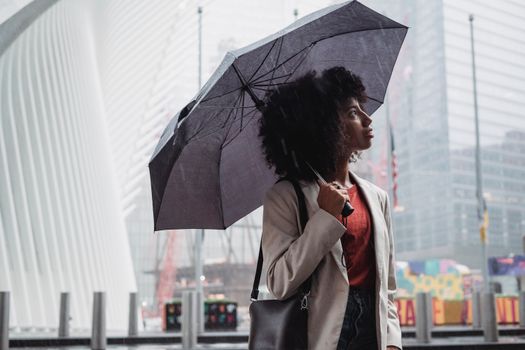 一个女人撑着雨伞，在多雨的城市天空下捕捉城市生活