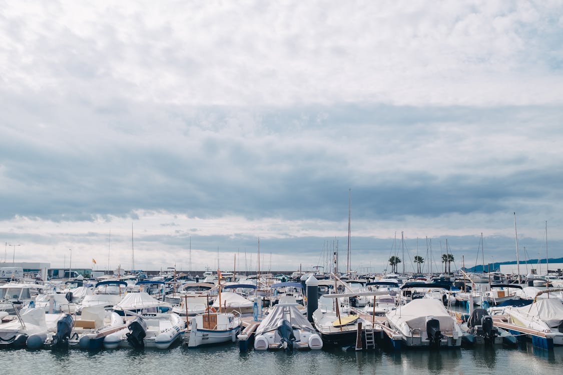 White and Blue Boats Docked on Water Under White Clouds