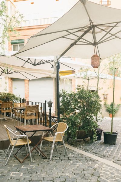 Cafe terrace with a wide canvas umbrella and wooden tables — photo by Leeloo The First on Pexels