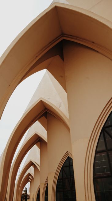 Facade of old historical building with tall beige arches and windows in sunlight