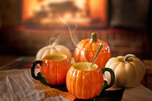 Free Warm autumn drinks in pumpkin mugs against a cozy fireplace setting. Stock Photo