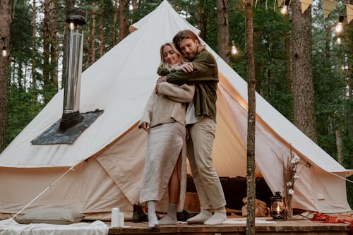 Photo of a Couple Hugging Near a White Tent