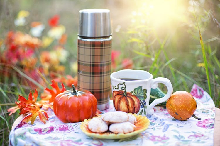 Close-Up Photograph Of A Vacuum Flask Beside A Cup Of Coffee