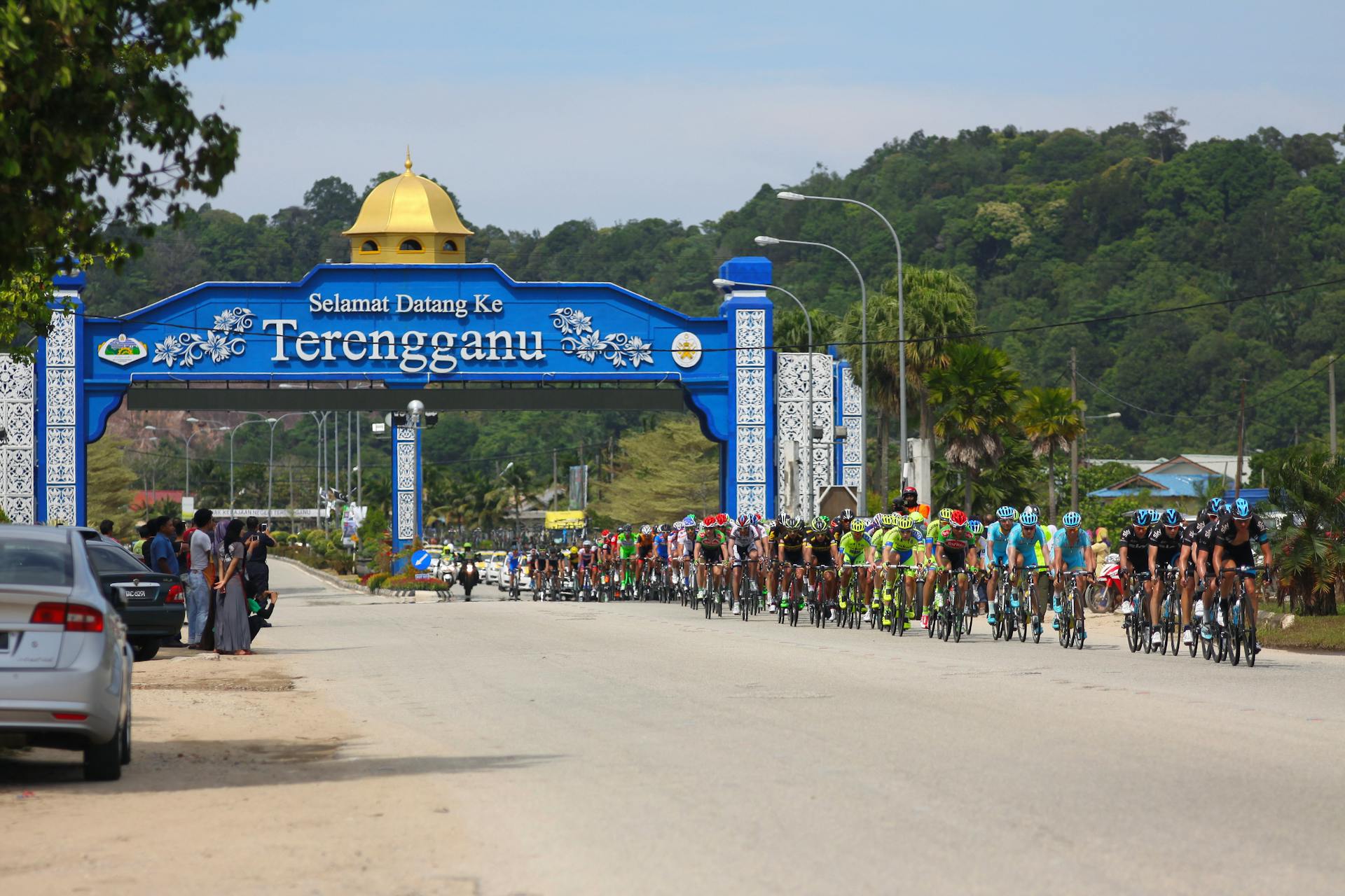 Professional cyclists in sportswear riding bicycles along asphalt road in tropical country during peloton competition