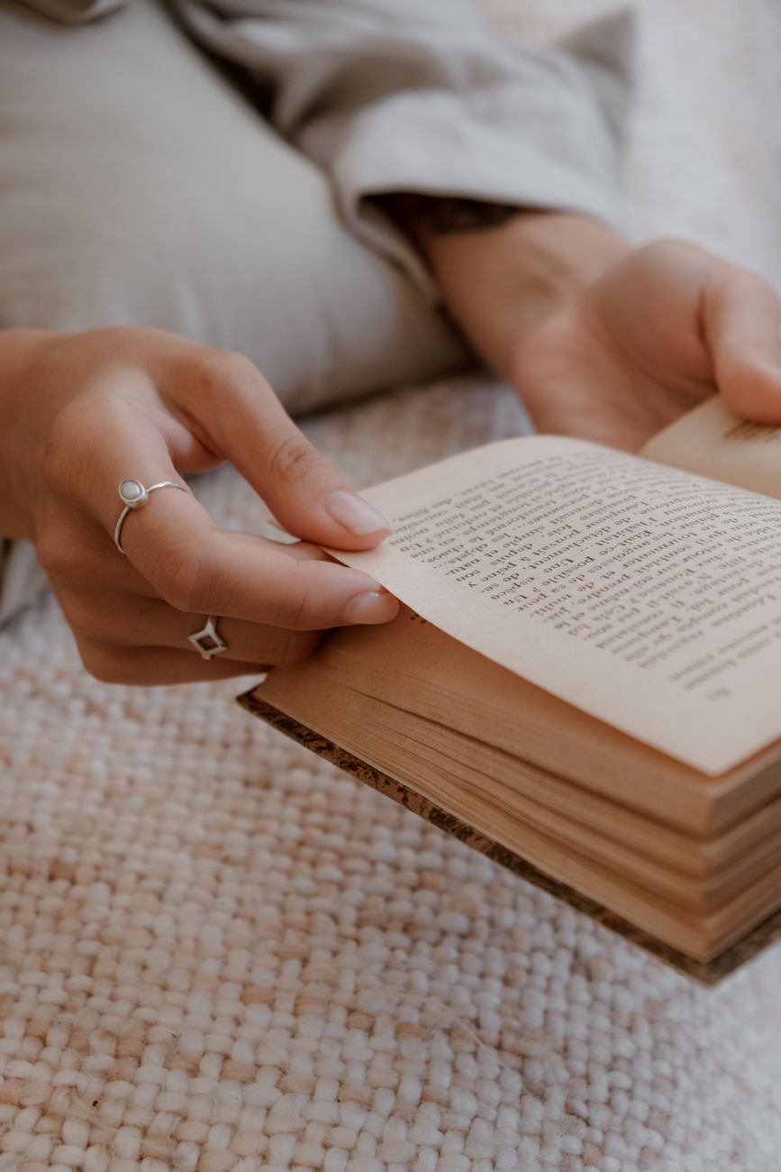 Stylish rings on hands flipping pages of an open vintage book.