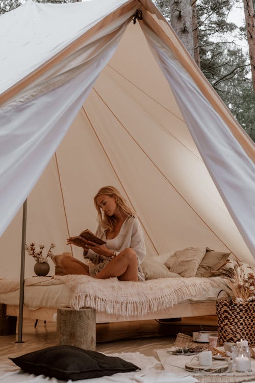 Free Woman Reading a Book in a White Tent Stock Photo