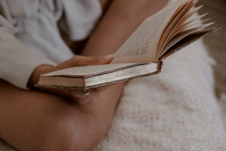 Photo Of A Person's Hand Holding A Worn Out Book