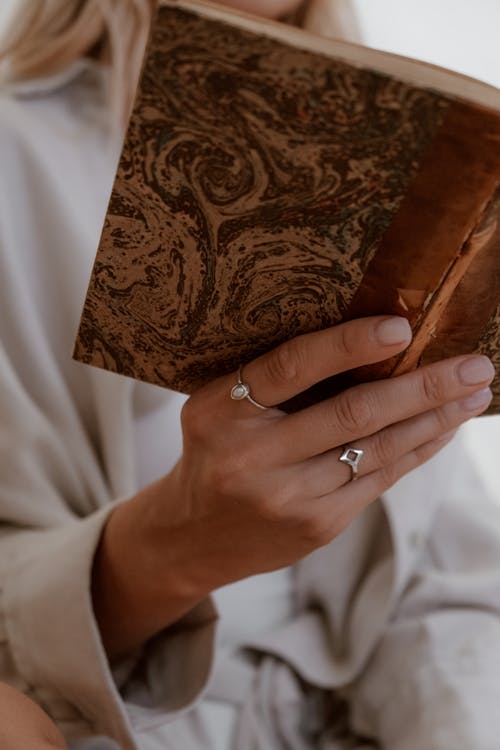 Free Photo of a Person's Hand Holding a Brown Book Stock Photo