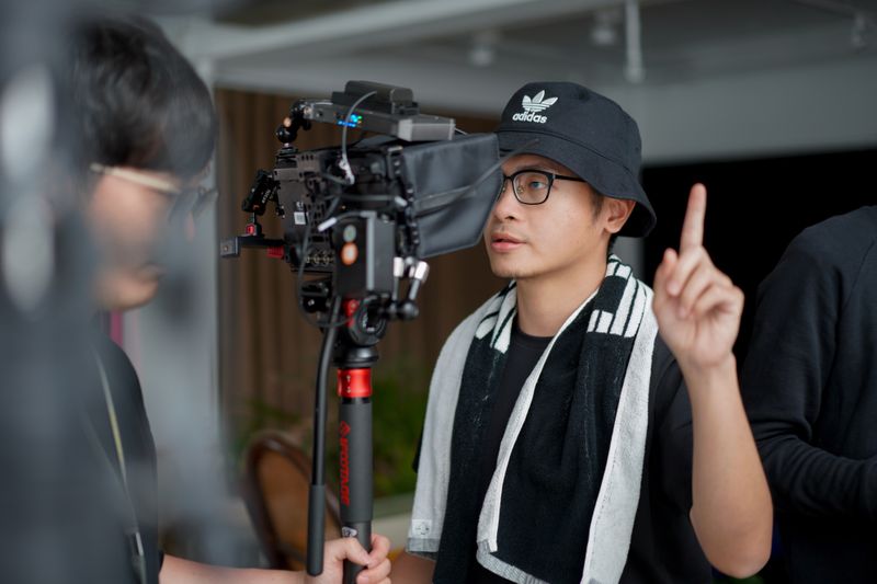 Director focused on managing film equipment and instructing crew indoors.