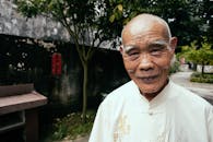 Smiling senior Asian man in traditional wear on street