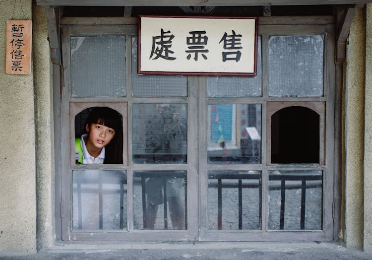 Attentive Asian Teen Looking Out Of Window In House