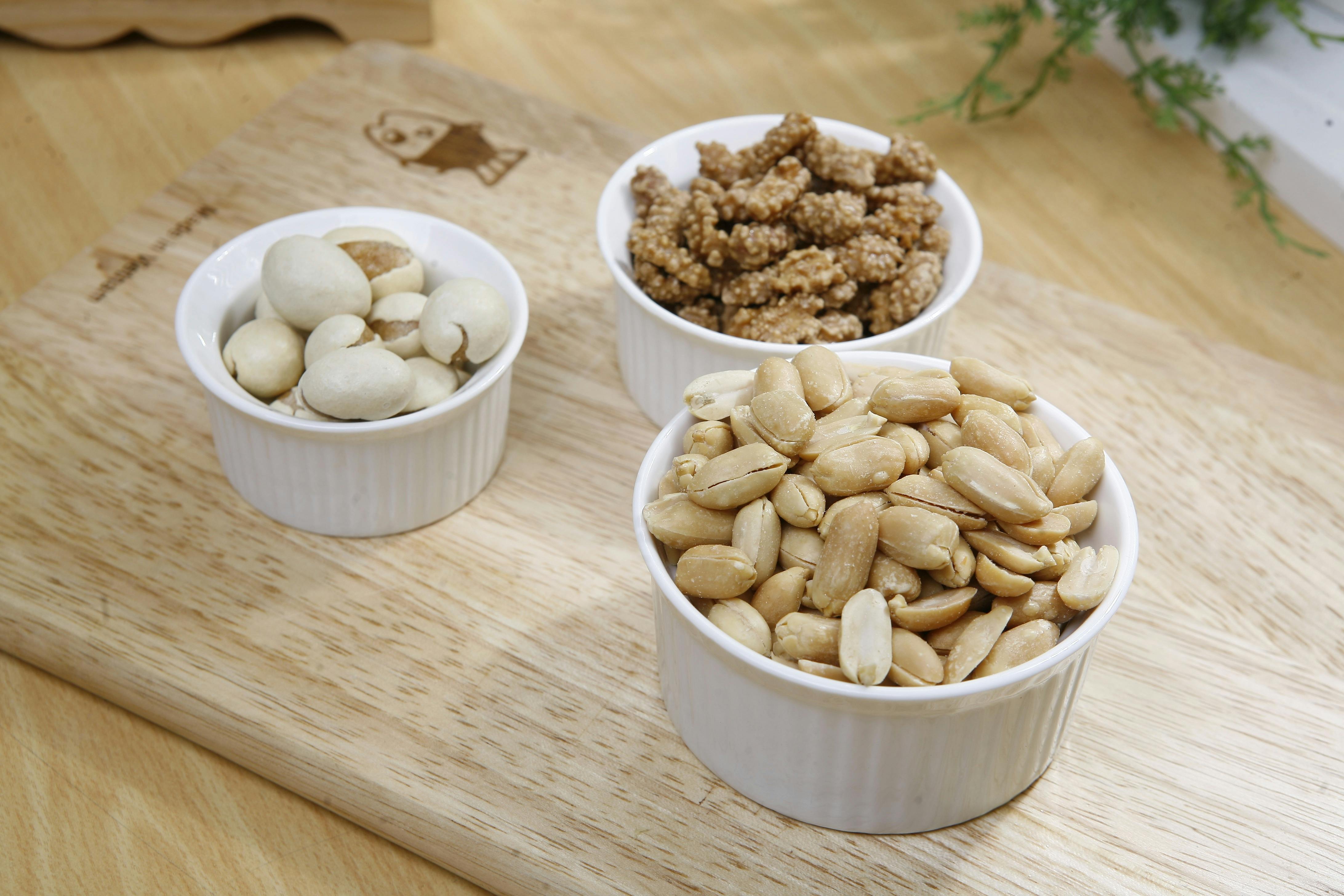 Close-up of various nuts in bowls on a wooden chopping board, perfect for food presentations.