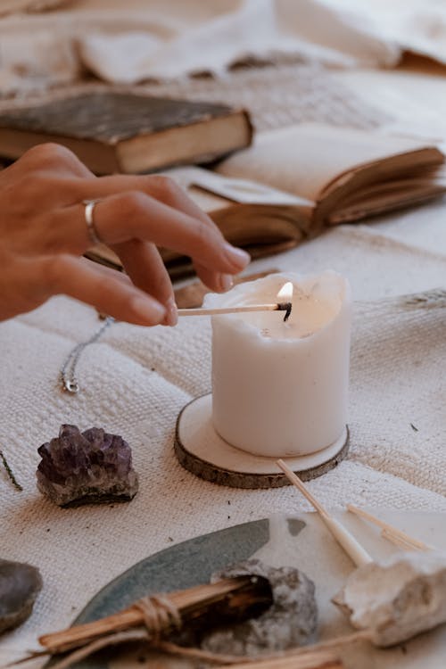 Photo of a Person Holding a Match Stick to Light a Candle