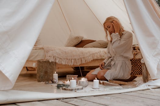 A woman enjoys a peaceful glamping moment, surrounded by candles in a cozy tent.