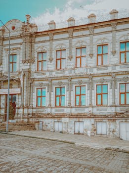 An elegant historic building with ornate details and a cobblestone street, showcasing classic architecture.