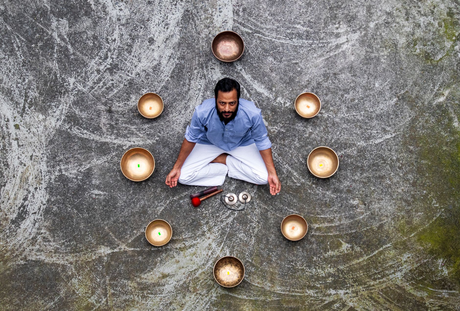 Man meditating surrounded by singing bowls in Pokhara, Nepal, promoting tranquility and mindfulness.