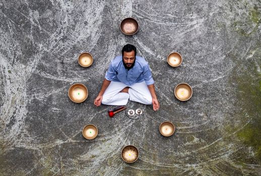 Man meditating surrounded by singing bowls in Pokhara, Nepal, promoting tranquility and mindfulness.