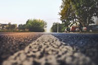 雾气弥漫的郊区街道上，路边停着汽车，树木在晨雾中若隐若现