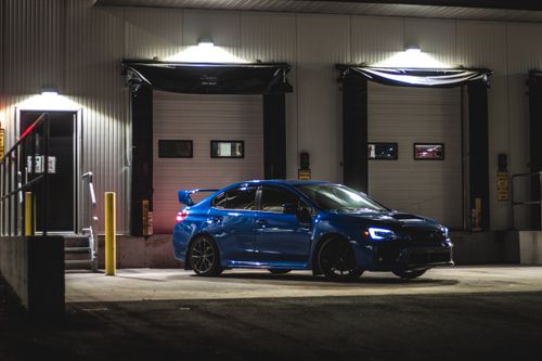 Free A luxury blue sportscar parked at night in an urban environment, under bright lights. Stock Photo