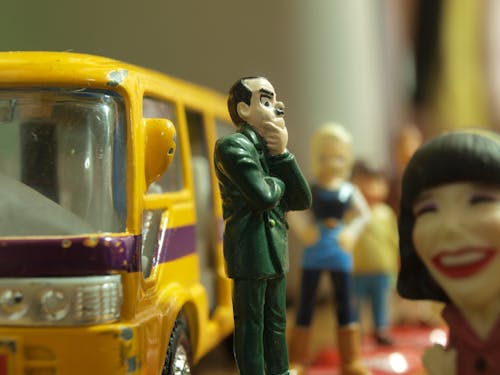 Hombre Con Abrigo Verde Figura De Pie Delante Del Autobús De Juguete Amarillo